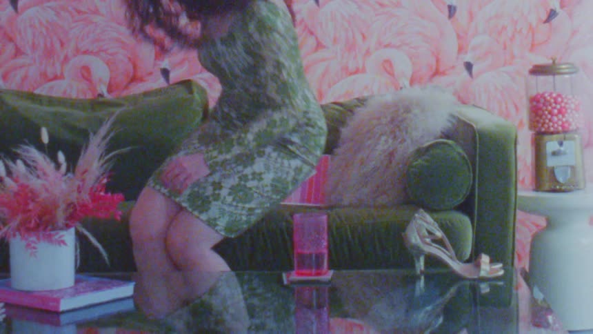 A woman eats candy from the candy machine then reads a book on the couch