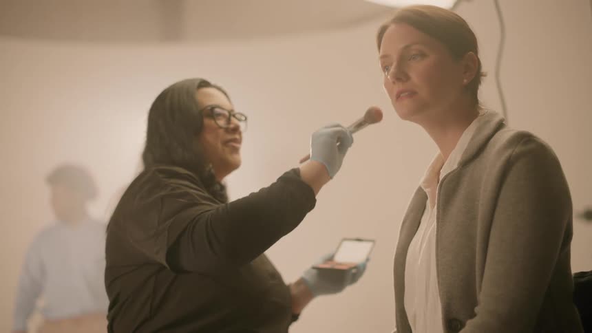 A makeup artist applying makeup on an actress in a studio