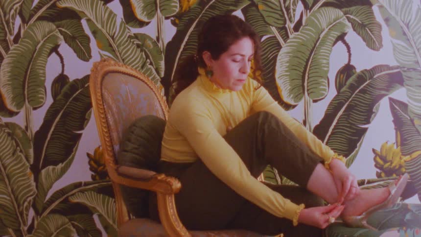 Woman sitting in chair putting on high heel sandals and strapping them on