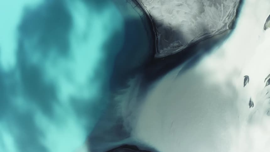 Extreme closeup and a light blue colored liquid next to a whitish snow in daylight
