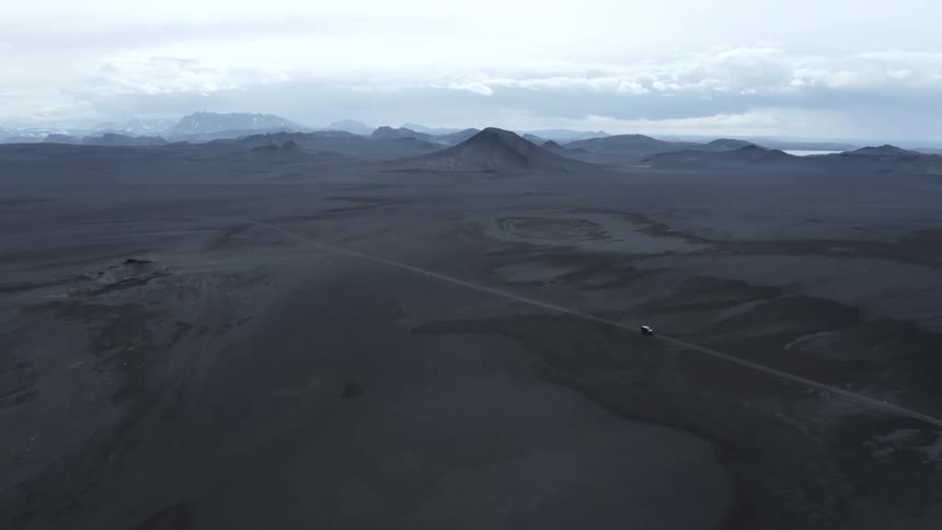A car is traveling on a dirt road near the mountains