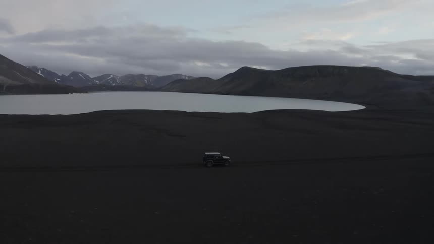 A vehicle drives past the lake