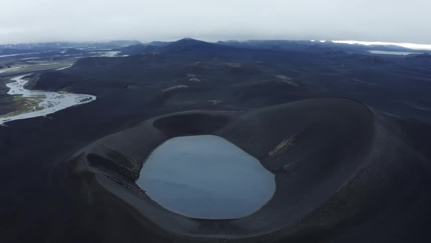 An aerial view of a lake in a crater at the top of a mountain