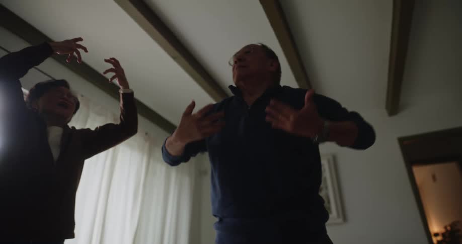Elderly husband and wife doing stretching excersises indoors