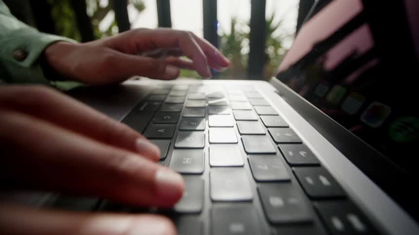 Woman typing on a laptop while sitting outside
