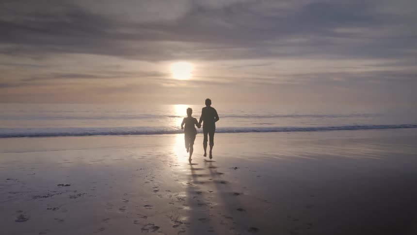 A clip of a couple on the beach running toward the sea
