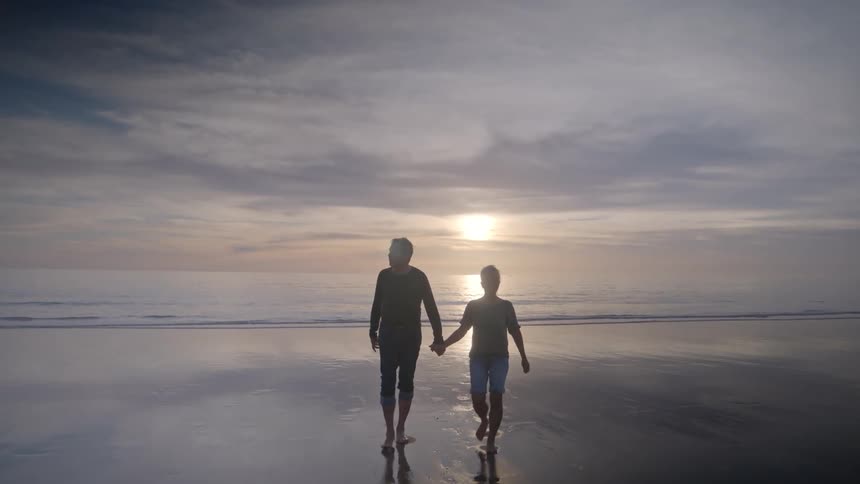 Man and woman holding hands and walking on the beach