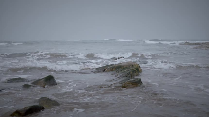 Ocean waves coming near the coast on a cloudy day
