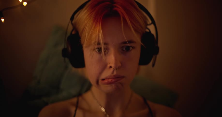 Female is wearing headphones and showing emotion while looking at something