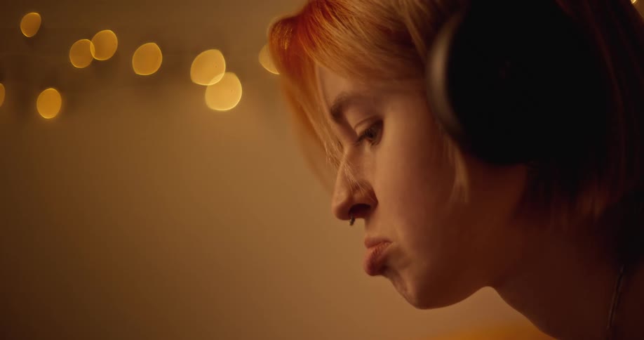 A woman is indoors and wearing a set of headphones