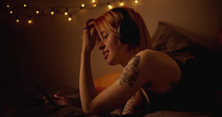 A woman with headphones texting on her phone