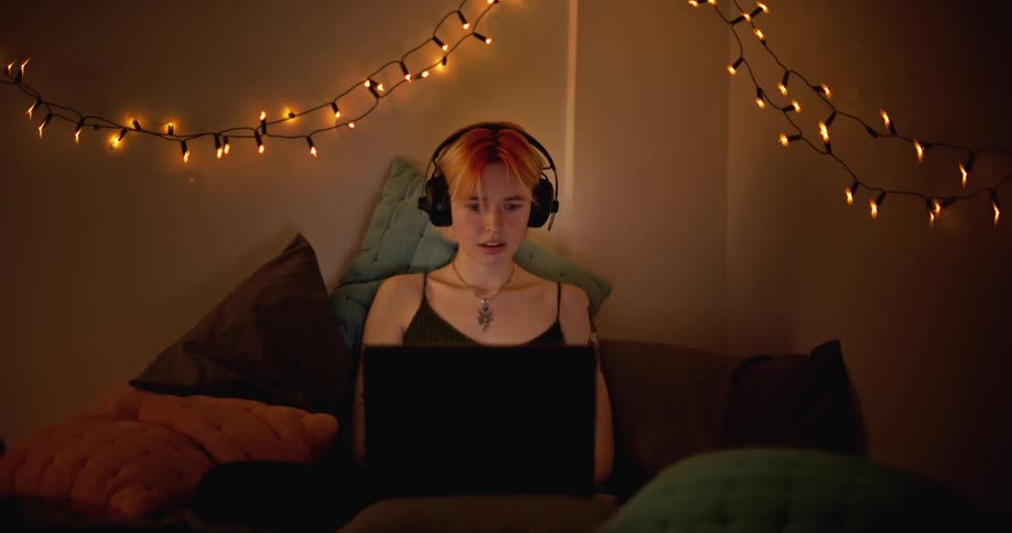 Woman is sitting on her bed and using a laptop