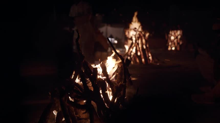 People sitting around campfires in the desert at night