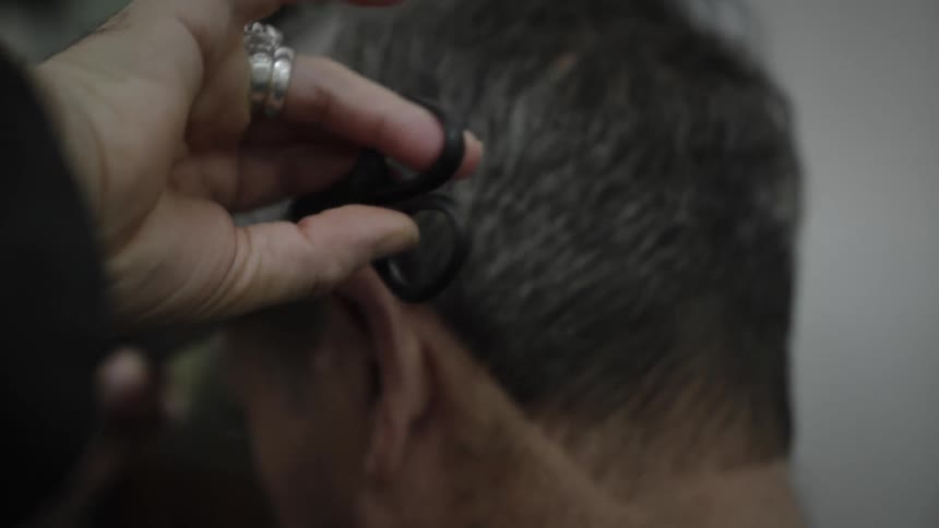 A man is getting a hair cut while sitting down