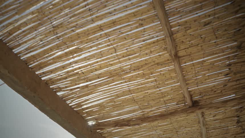 Homemade straw roof overlooking a blue sky and solar reflection