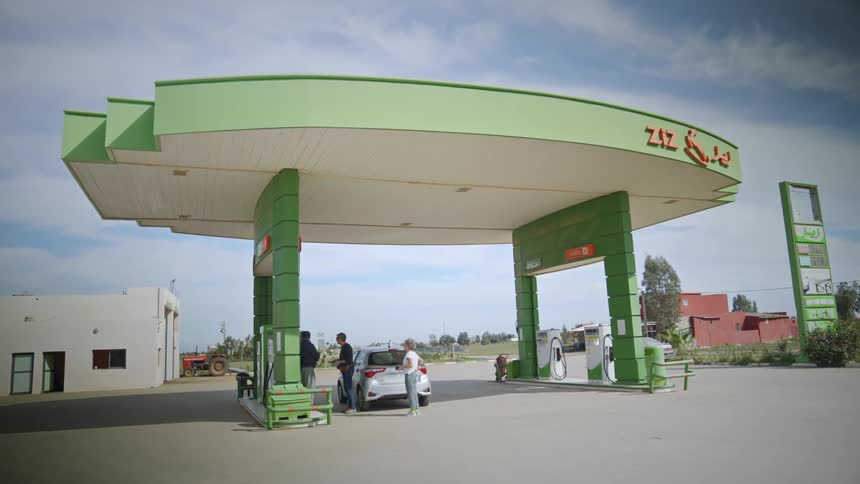 A group of people stand around waiting for their car to fill with fuel