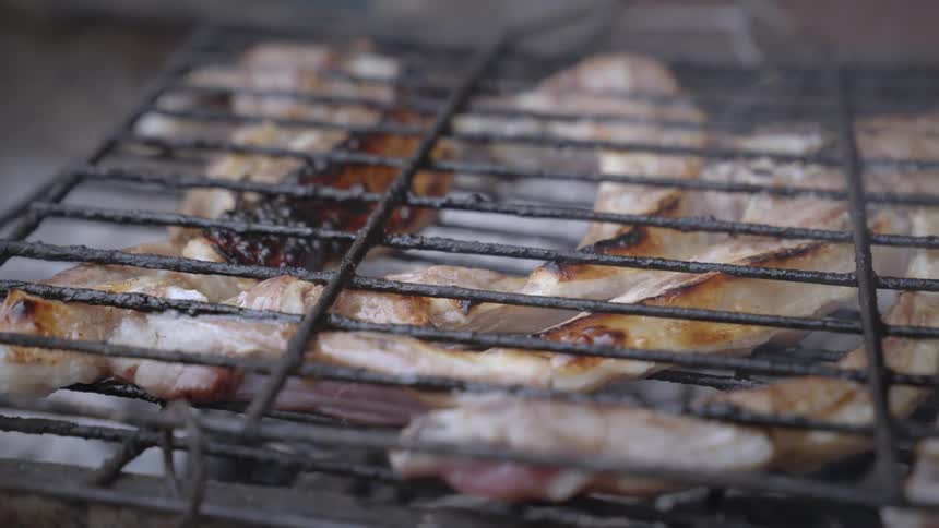 Pieces of meat with fat being roasted on a barbecue grill