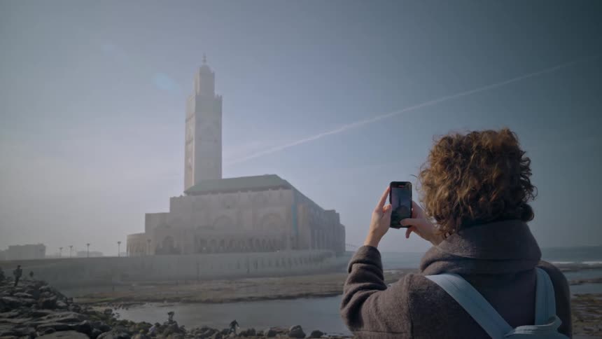 View of a tourist with his iphone camera photographing time at the seaside