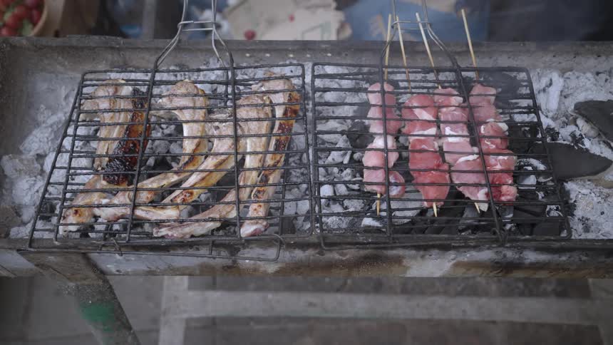 Pork and beef and on skewers being roasted on a coal