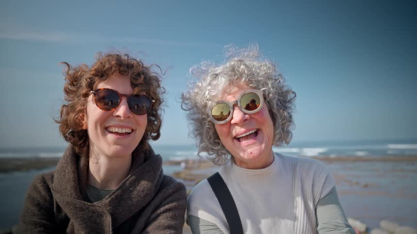 Two female friends outdoors at the beach and smiling