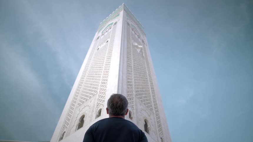 View of a man with his back looking up at an exterior architecture of a religious tower