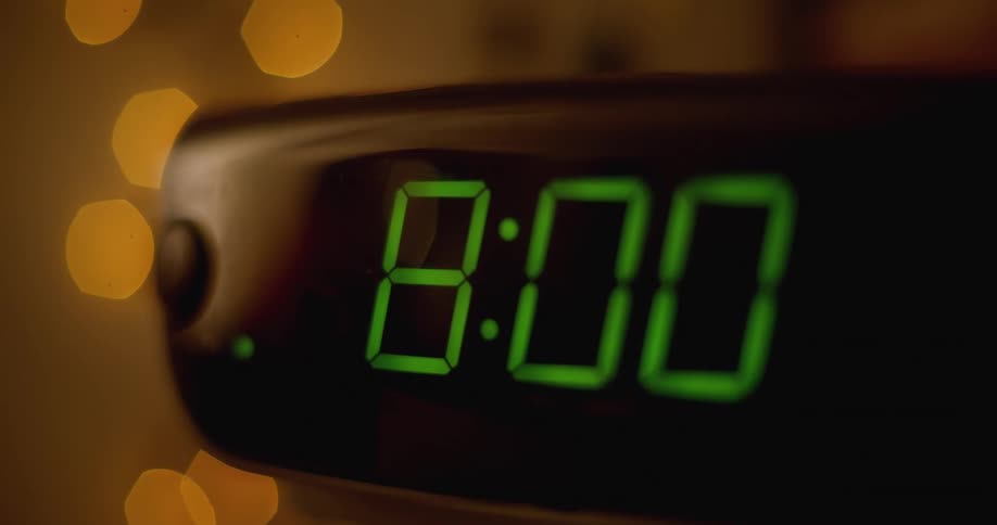 A person turns off their alarm clock