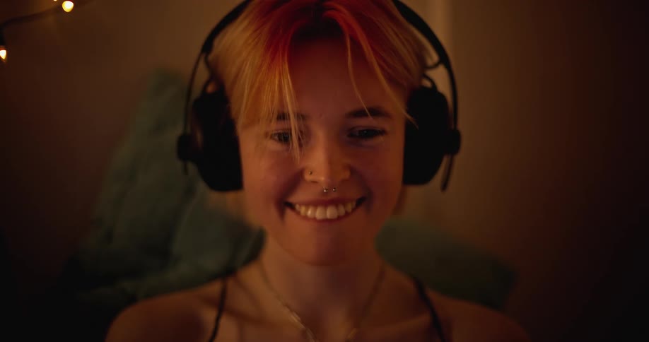 Woman wearing headphones laughs at something on her laptop