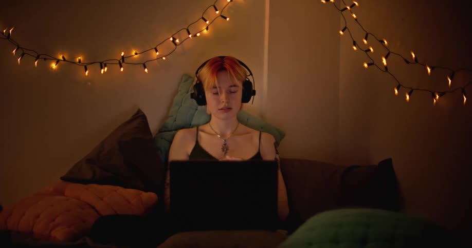 Female is browsing on her laptop and wearing headphones