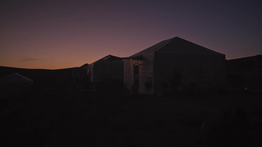A group of tents set in the desert at dusk