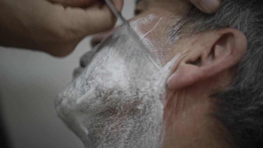 A man getting his beard shaved