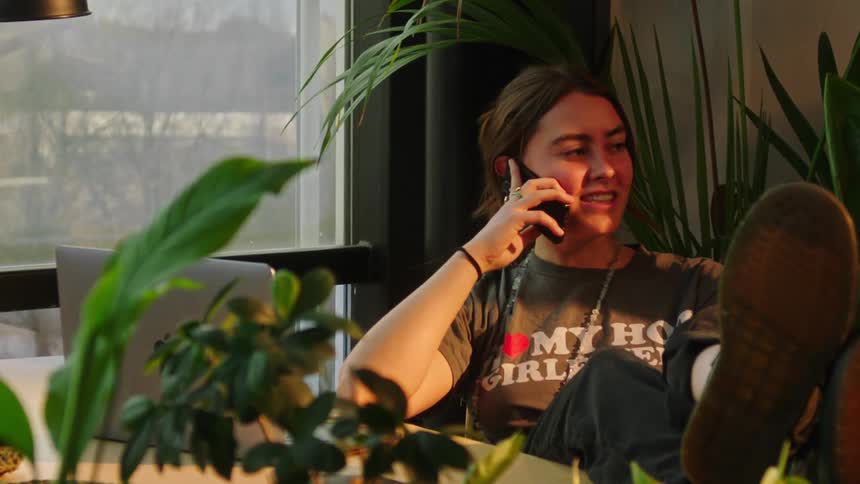 Female is sitting at a desk and talking on a cell phone