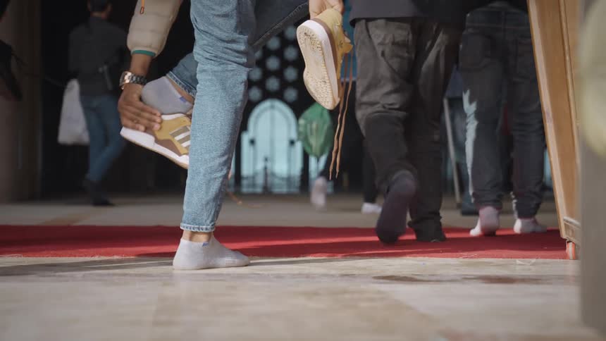 People taking their shoes off before entering a mosque