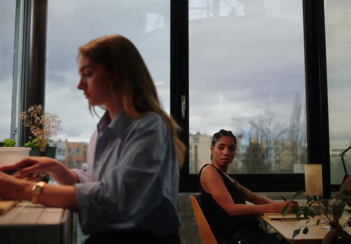 Woman concentrated cutting potatoes and next to her another woman working at an office table