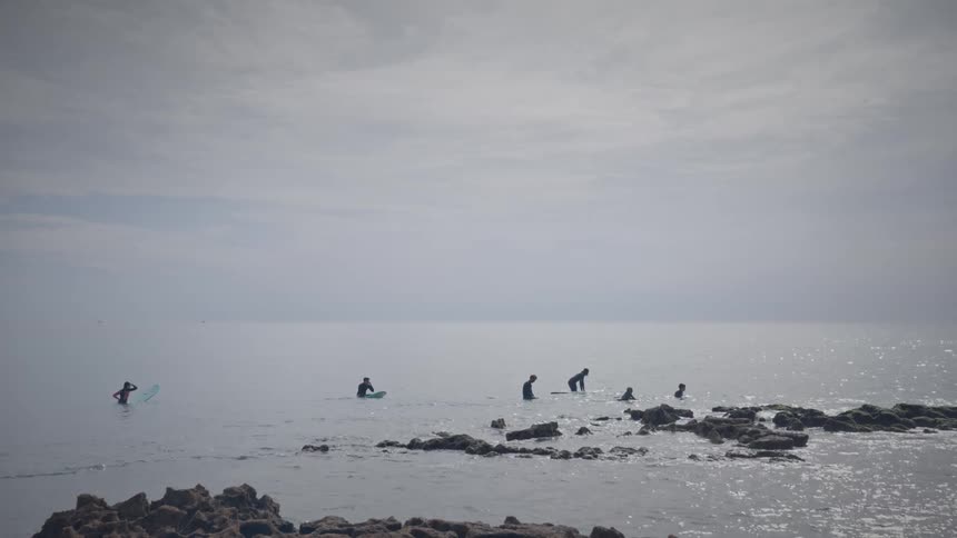 Surfers in the sea on a blue sky day with clouds