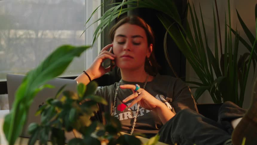 A woman is talking on the phone while looking out the window