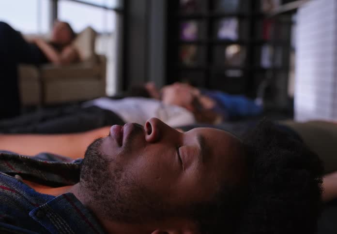 A group of people sleeping on the floor and couch of an office