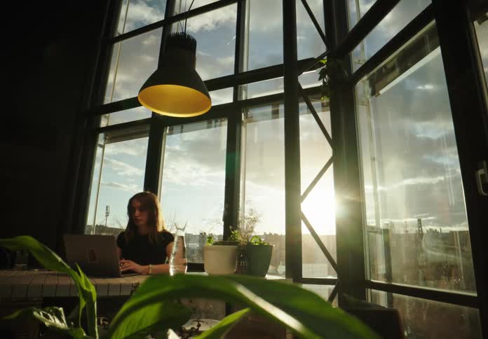 A woman is sitting in her office while typing on a laptop
