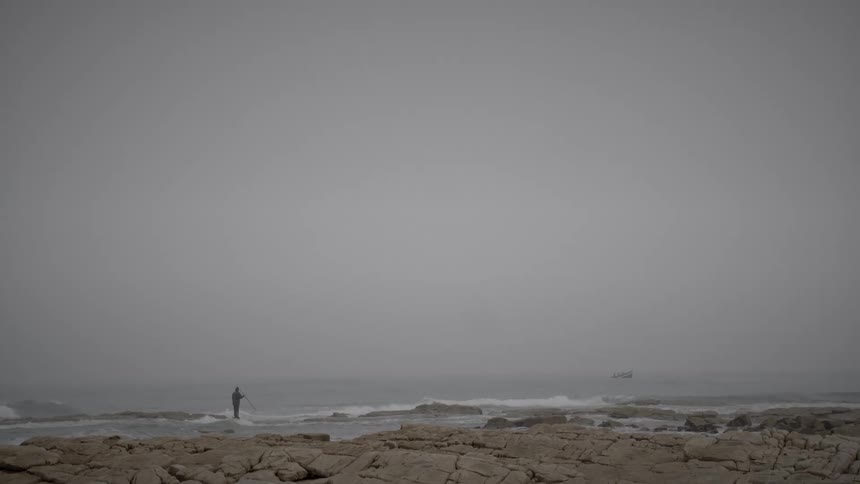 A man stands close to the surf on a beach