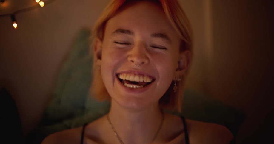 Close up of the face of a young woman laughing while looking at something on her laptop