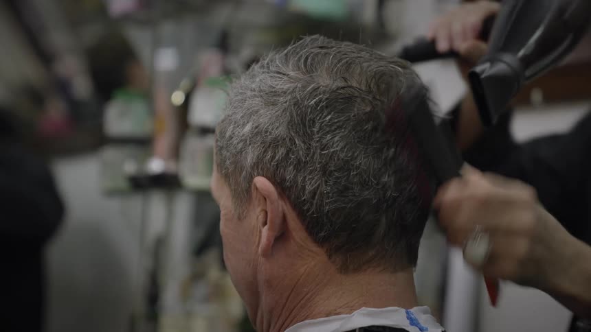 A hair stylist drying the hair of a client
