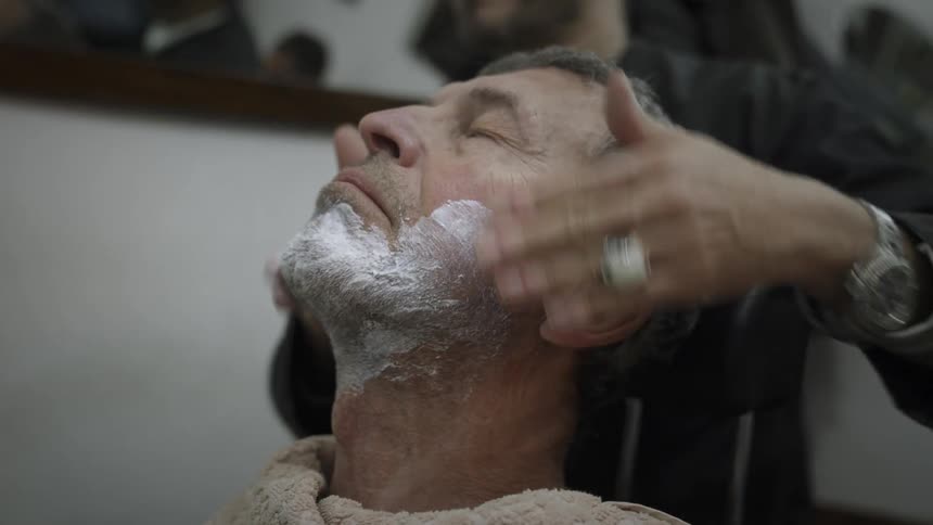 Man sitting in chair getting shaving cream applied