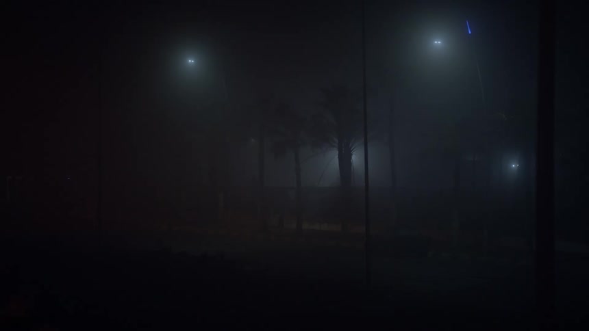 Dark street with low streetlights in fog in a city