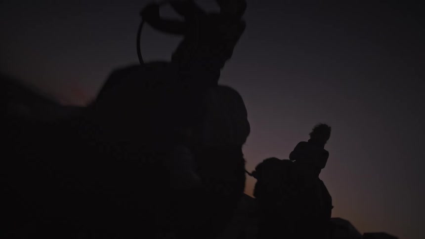 Silhouette of people riding camels in the desert at nightfall