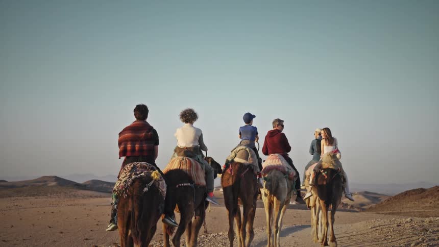 Group of people riding camels through the desert on an expedition