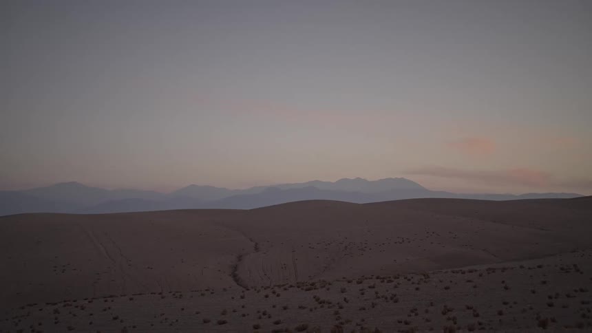 The sun is setting in the horizon of the desert landscape