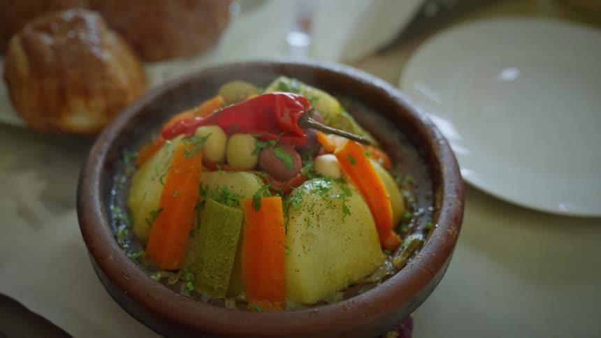 A womans hand opening a Tagine - a typical moroccan dish with steamed vegetables