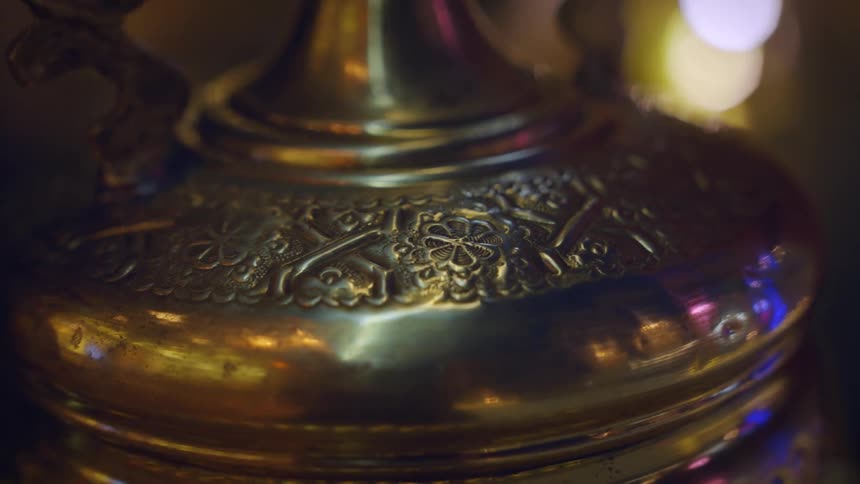 Closeup on a metallic and golden kettle with artistic designs