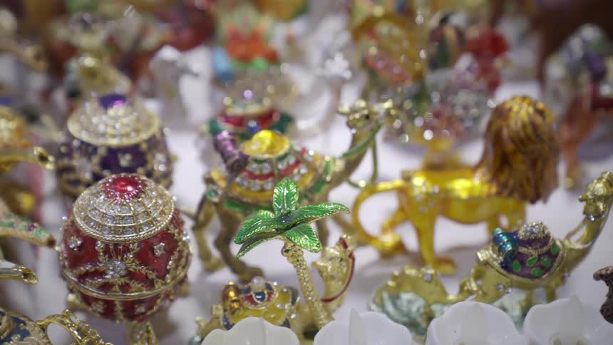Multiple small figurines are painted brightly and covered in gemstones