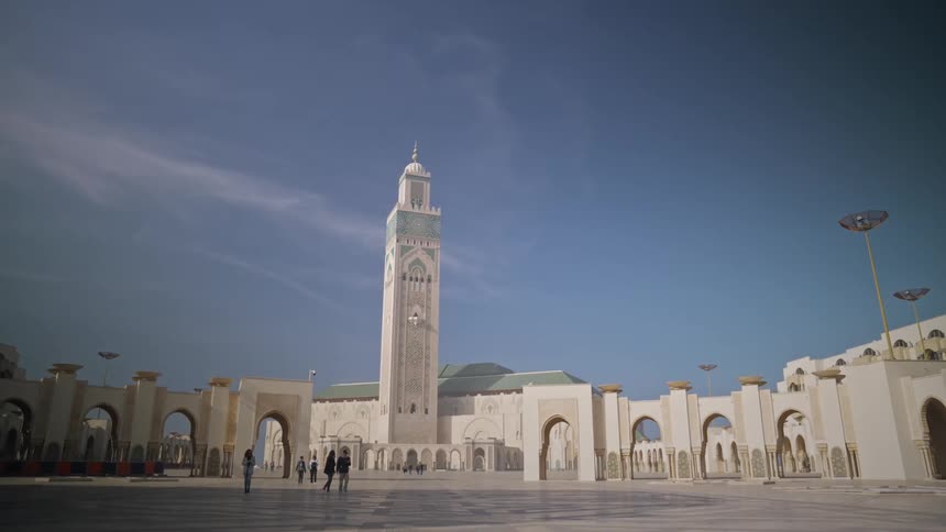 People walking on the hassan ii mosque under a blue sky