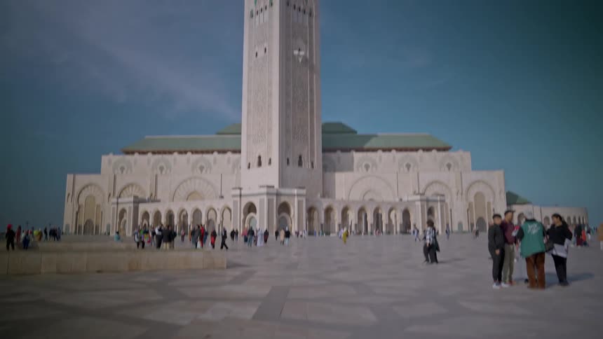 Exterior view of a religious temple with crowd of people walking around hassan mosque